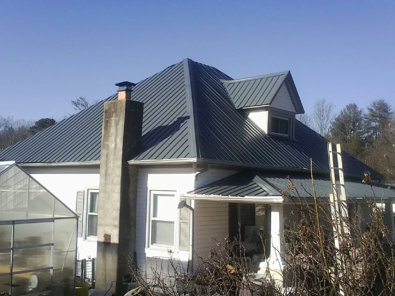 Dark blue standing seam metal roof on a white farmhouse with dormer — Slate & Tile Roof Repair by Roofing Brothers in Amenia