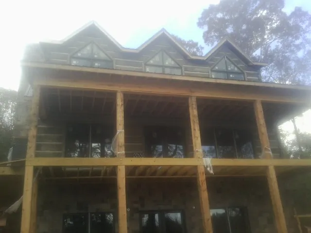 Dormers and porch framing on a large log home under construction — Roof Coating work by our crew in Amenia