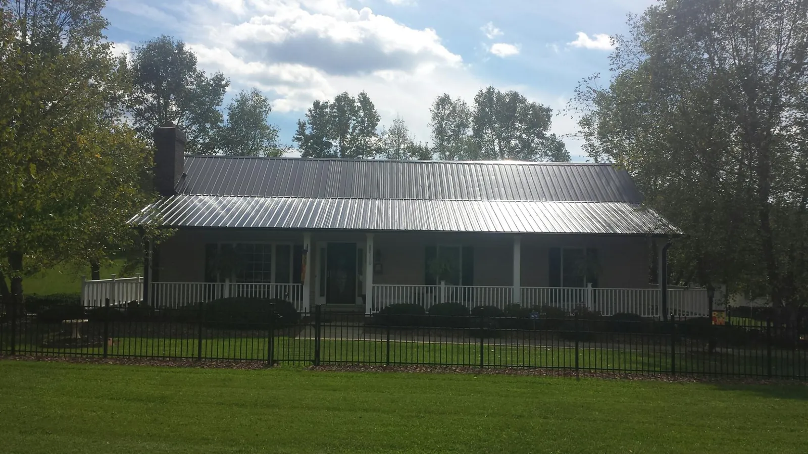 Gray metal roof on a brick ranch with a full width front porch — Gutter Guard Installation work by our crew in Amenia