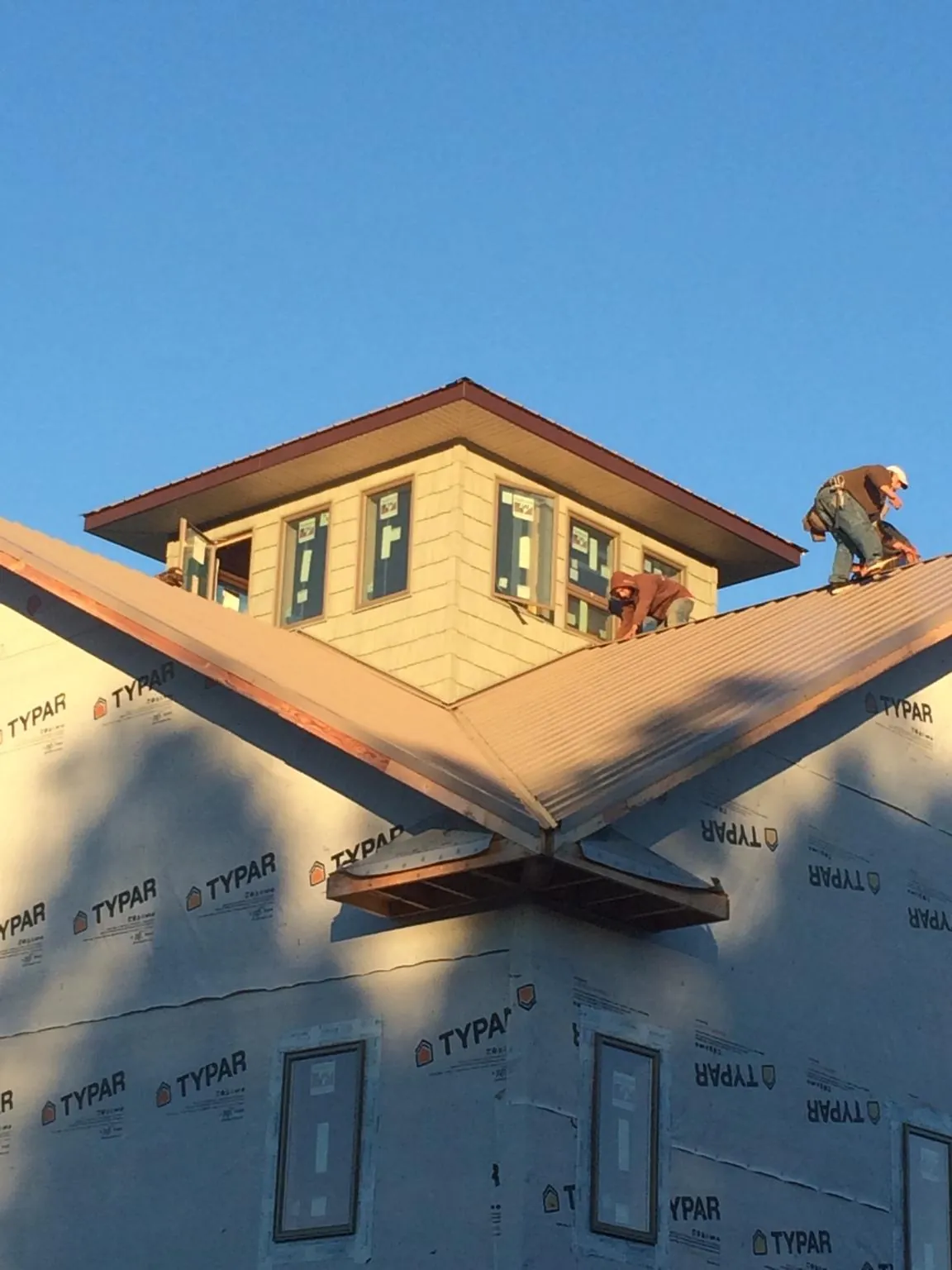 Roofers working around a rooftop cupola on a new metal roof at sunset — Roof Waterproofing in Amenia by Roofing Brothers